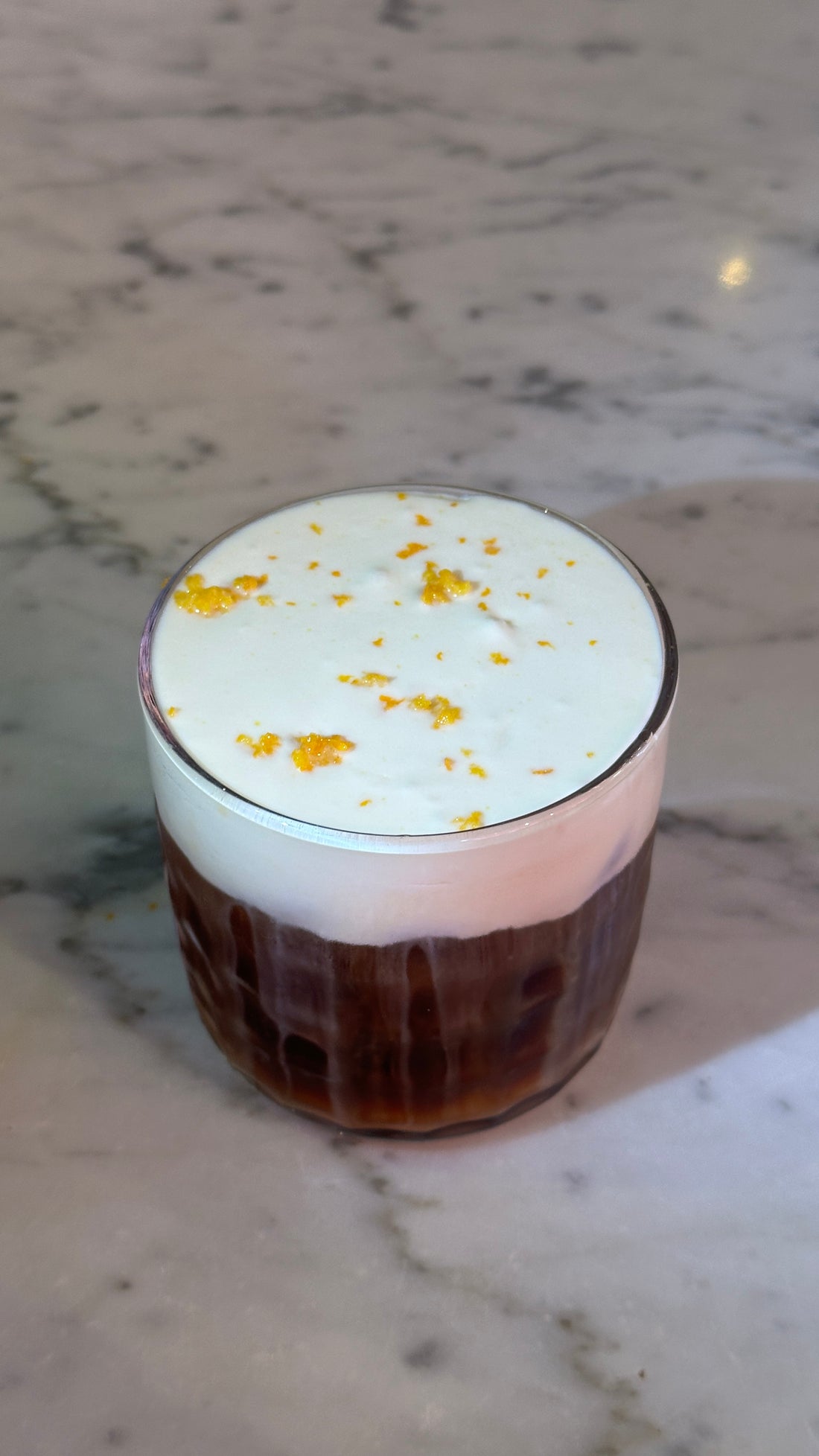 Iced coffee with cream foam and orange zest at Brü Basel